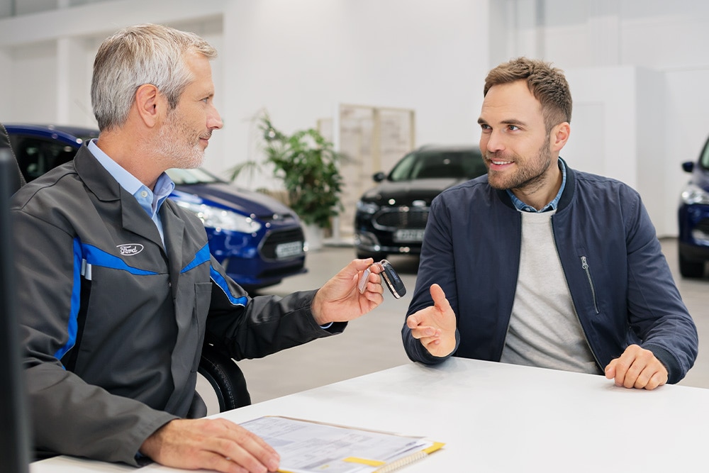 ford e_transit_custom eu Column_Card_2016_E_Showroom_017 3x2 1000x667 two men in ford office